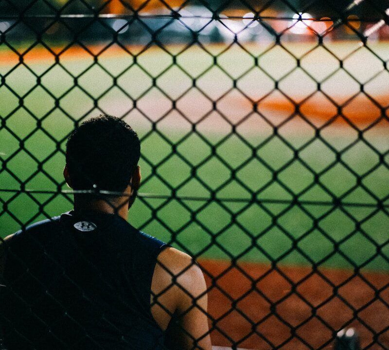 a man sitting on a bench watching a baseball game