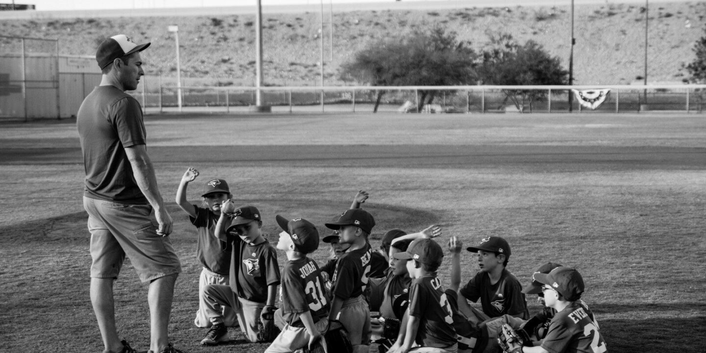 grayscale photo of boys football team in front of coach
